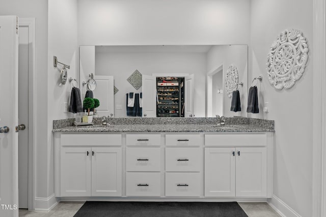 bathroom with a sink, baseboards, and double vanity