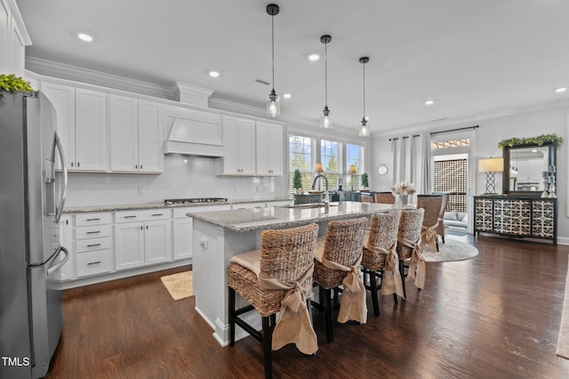 kitchen with a sink, appliances with stainless steel finishes, crown molding, and premium range hood