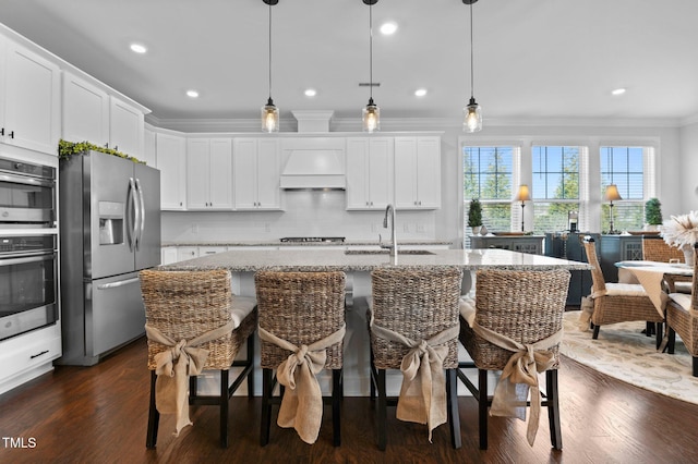 kitchen featuring premium range hood, a sink, light stone counters, stainless steel appliances, and crown molding