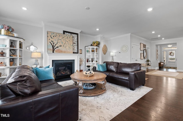 living room featuring wood finished floors, baseboards, recessed lighting, a glass covered fireplace, and crown molding