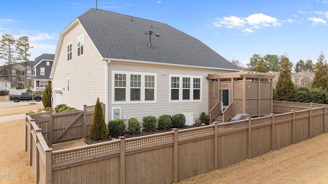 back of house featuring roof with shingles, a fenced backyard, and entry steps