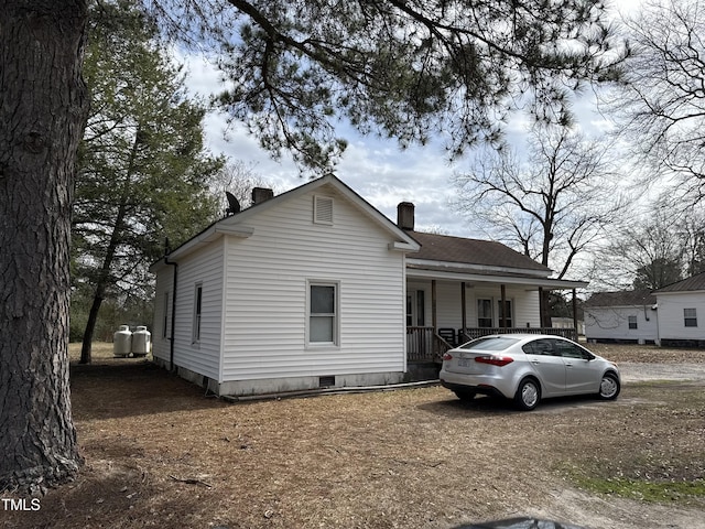 view of front facade featuring crawl space, covered porch, and a chimney