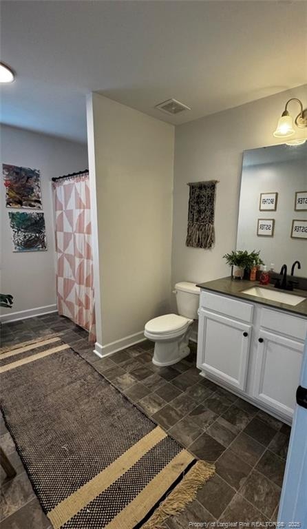 full bathroom featuring visible vents, stone finish flooring, baseboards, toilet, and vanity