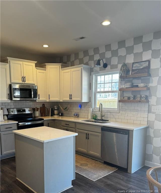 kitchen featuring visible vents, a sink, light countertops, appliances with stainless steel finishes, and dark wood-style flooring