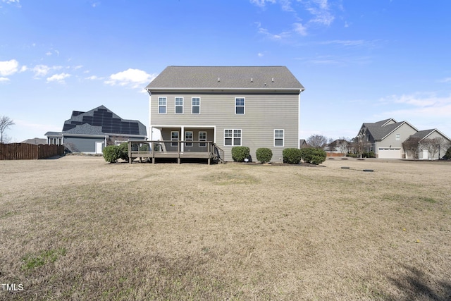 rear view of property featuring a lawn, fence, and a wooden deck