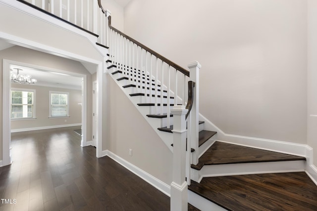 stairs featuring an inviting chandelier, a high ceiling, baseboards, and wood finished floors