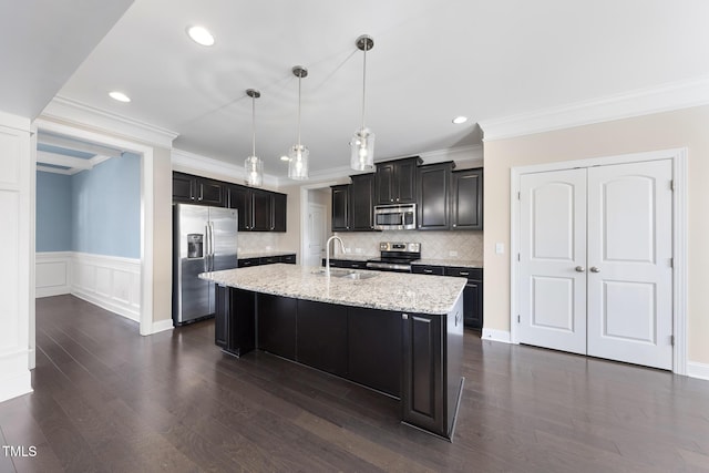 kitchen with light stone counters, dark wood-style flooring, a sink, appliances with stainless steel finishes, and dark cabinets