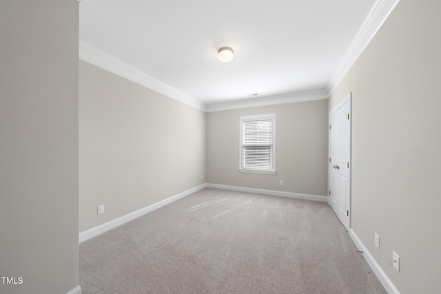 empty room with crown molding, light colored carpet, and baseboards