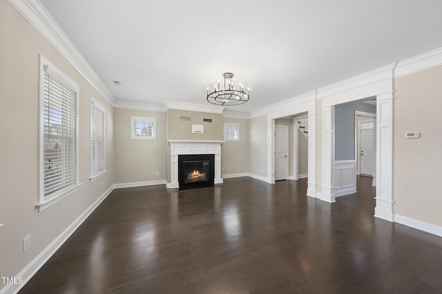 unfurnished living room featuring baseboards, dark wood finished floors, a fireplace with flush hearth, ornamental molding, and a notable chandelier