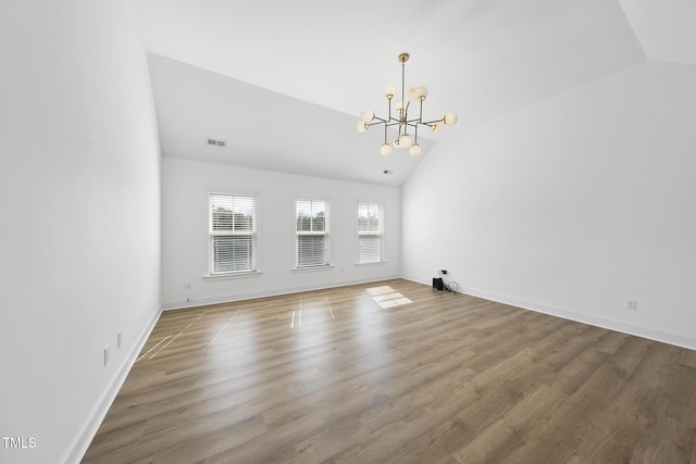 interior space featuring wood finished floors, visible vents, baseboards, vaulted ceiling, and a notable chandelier