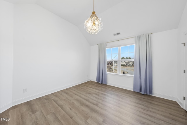 unfurnished room with visible vents, baseboards, lofted ceiling, wood finished floors, and a notable chandelier