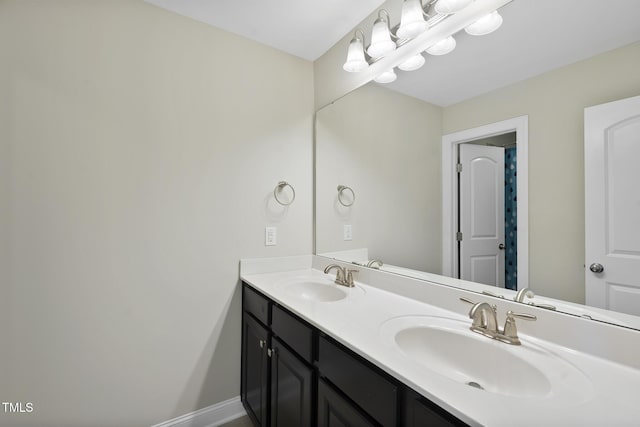 full bathroom featuring a sink, baseboards, and double vanity