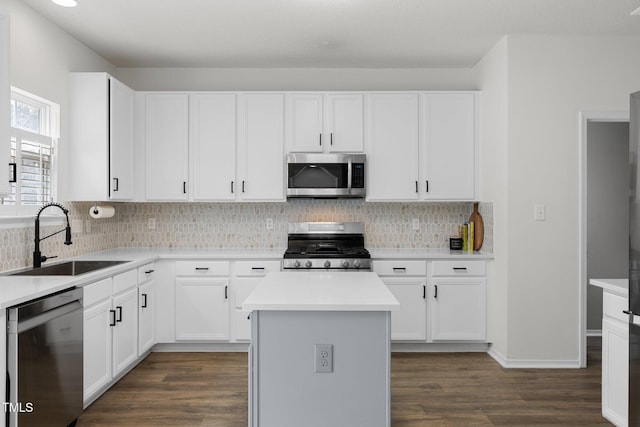 kitchen with dark wood-type flooring, a sink, tasteful backsplash, a center island, and stainless steel appliances