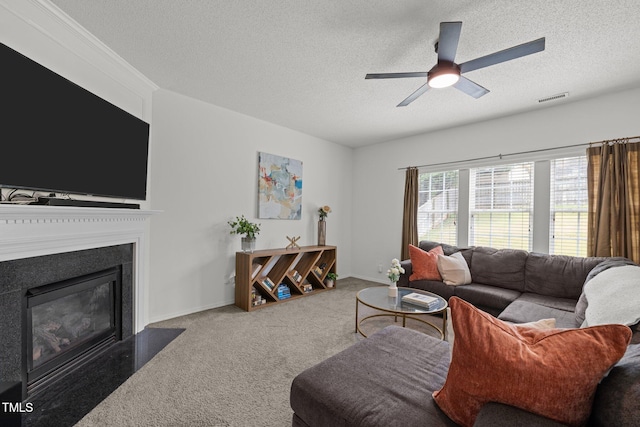 carpeted living area featuring visible vents, a fireplace with flush hearth, a textured ceiling, baseboards, and ceiling fan