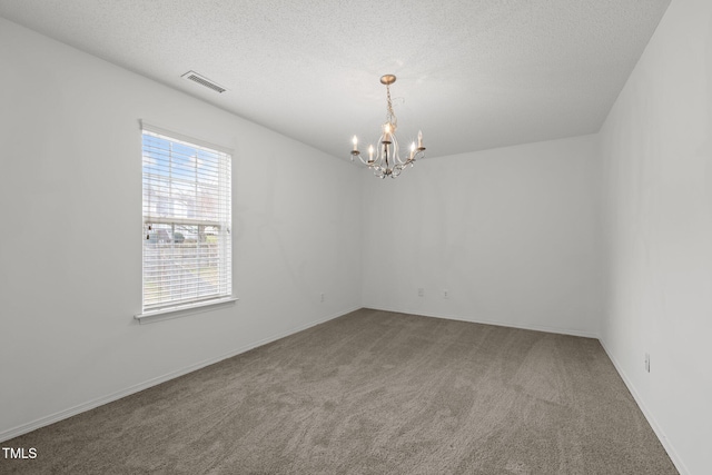 carpeted spare room with visible vents, a textured ceiling, and an inviting chandelier