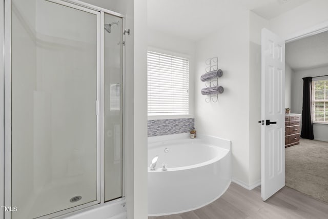 full bathroom with a shower stall, a garden tub, and wood finished floors