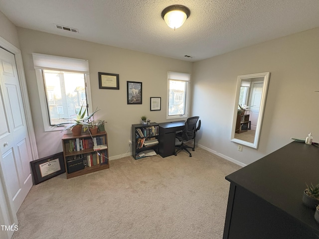 carpeted office space with visible vents, a textured ceiling, and baseboards