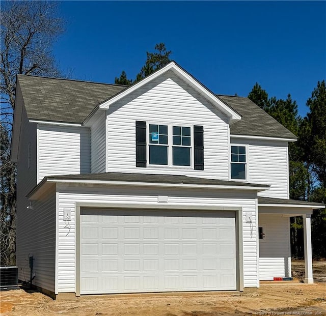 view of front of house featuring central AC unit, an attached garage, and dirt driveway