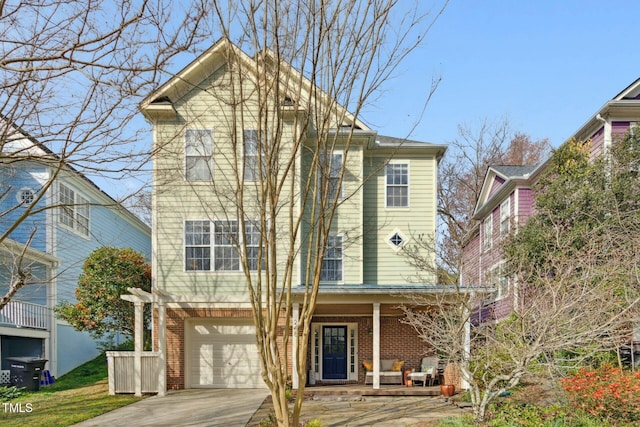 traditional-style home featuring an attached garage, brick siding, covered porch, and driveway