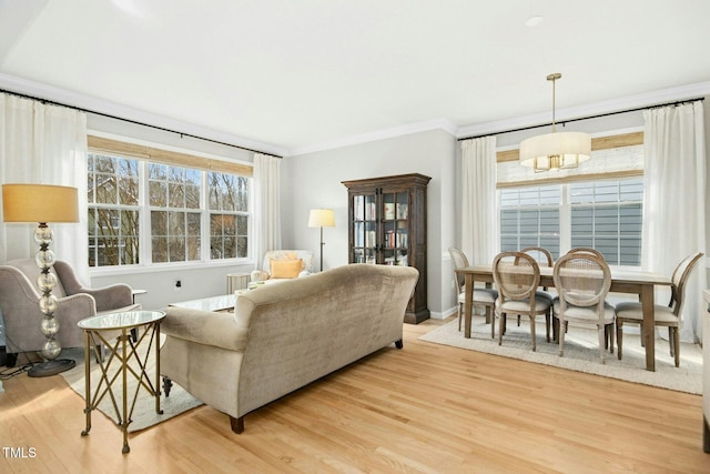 living room with light wood finished floors, baseboards, and ornamental molding