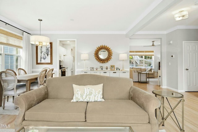 living room with light wood-style flooring, crown molding, and baseboards