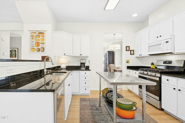 kitchen with dark countertops, white cabinetry, stainless steel appliances, and a sink