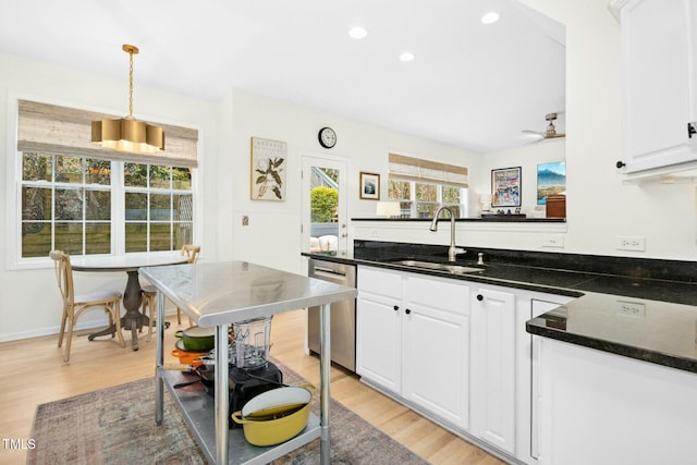 kitchen with a sink, light wood-type flooring, stainless steel dishwasher, and white cabinets