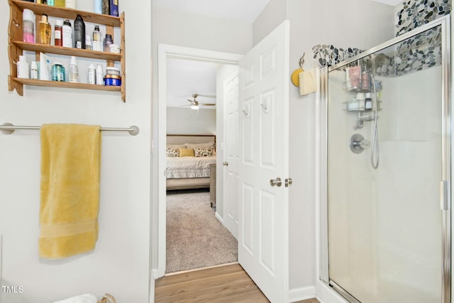 ensuite bathroom featuring a ceiling fan, a shower stall, wood finished floors, and ensuite bathroom