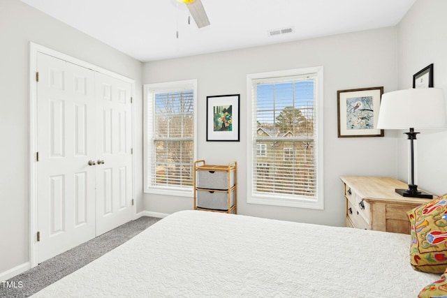 carpeted bedroom with visible vents, baseboards, a closet, and ceiling fan