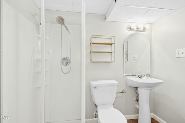 full bathroom with baseboards, a paneled ceiling, toilet, and a shower stall