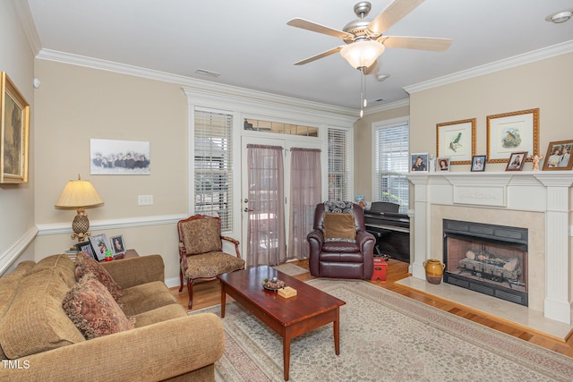 living room featuring visible vents, ornamental molding, a ceiling fan, wood finished floors, and a high end fireplace