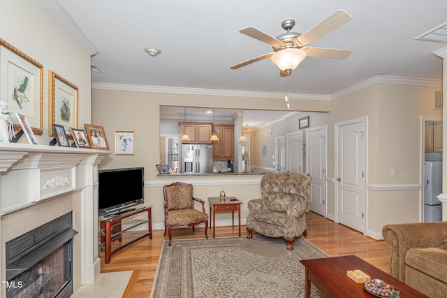 living area with crown molding, baseboards, ceiling fan, a fireplace with flush hearth, and light wood-style flooring