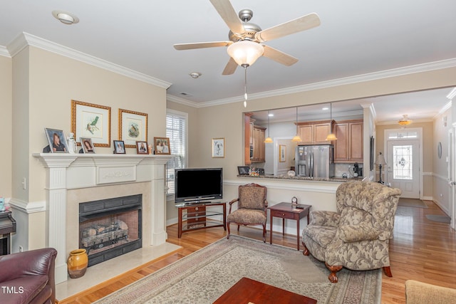 living room featuring crown molding, a fireplace with flush hearth, baseboards, and light wood-type flooring