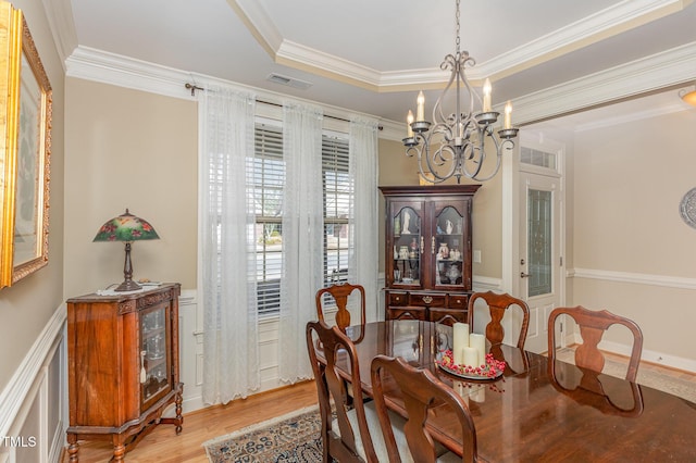 dining room with visible vents, wood finished floors, crown molding, a raised ceiling, and a chandelier