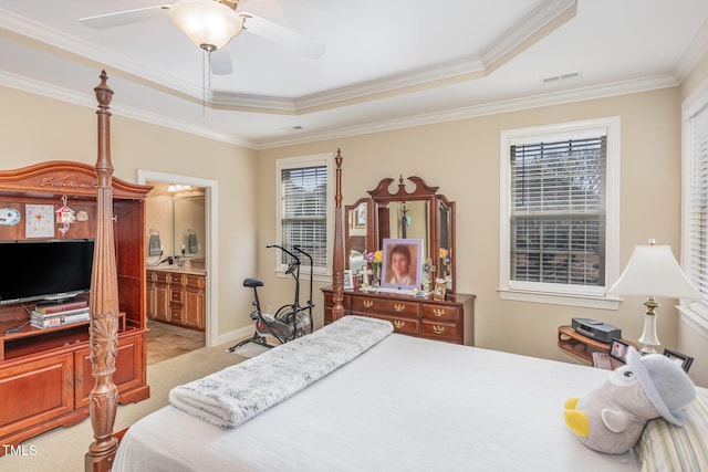 bedroom with ensuite bath, light colored carpet, visible vents, and a raised ceiling