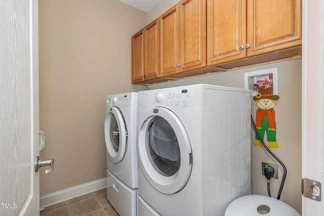 washroom featuring light tile patterned floors, baseboards, cabinet space, and washer and clothes dryer