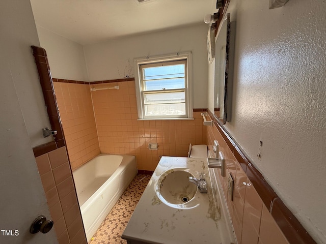 bathroom with walk in shower, a washtub, vanity, wainscoting, and tile walls