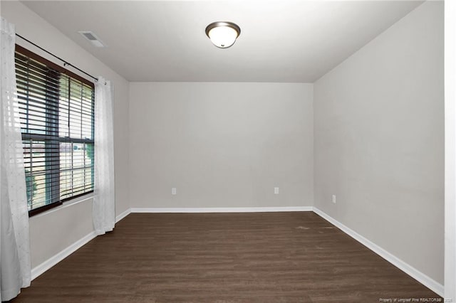 spare room featuring dark wood finished floors, visible vents, and baseboards