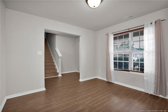 empty room with dark wood finished floors, stairs, baseboards, and visible vents