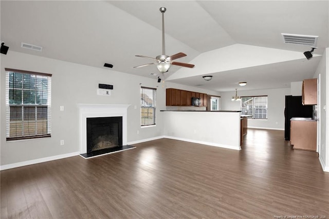 unfurnished living room with a ceiling fan, a fireplace with raised hearth, visible vents, and dark wood-style flooring