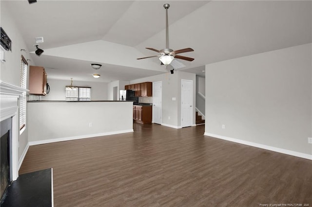 unfurnished living room featuring ceiling fan with notable chandelier, dark wood finished floors, a high end fireplace, baseboards, and vaulted ceiling