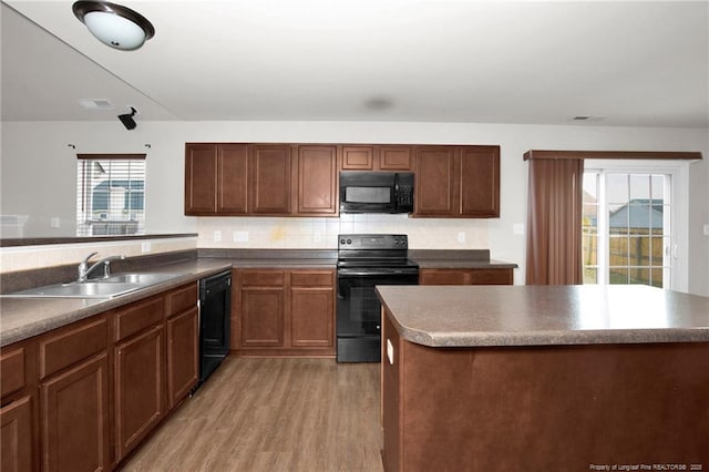 kitchen featuring visible vents, backsplash, light wood-style floors, black appliances, and a sink