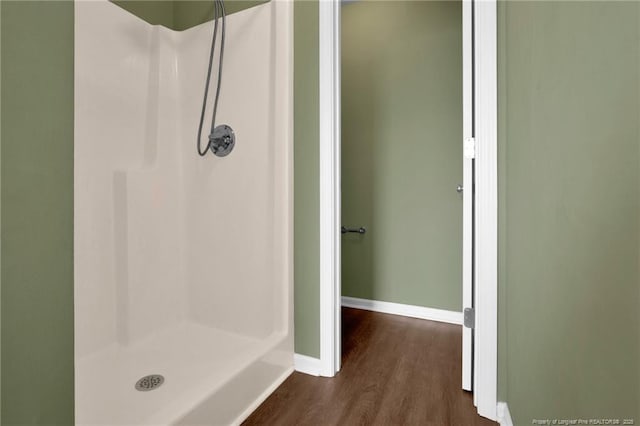 full bath with a shower stall, wood finished floors, and baseboards