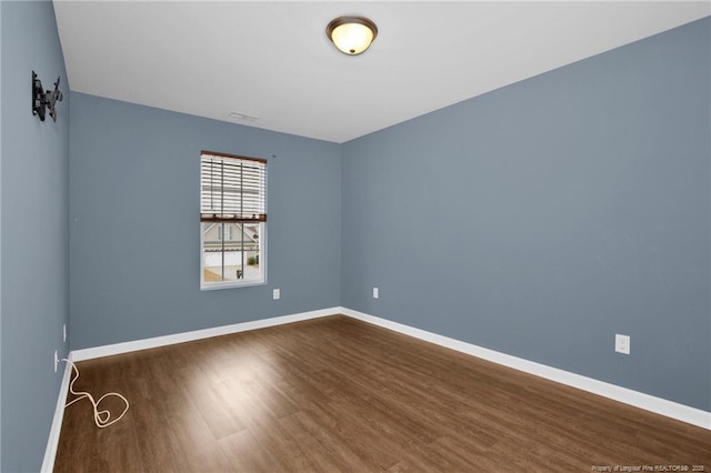 unfurnished room with dark wood-type flooring and baseboards