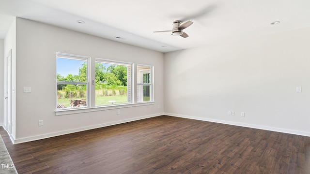 empty room featuring a ceiling fan, visible vents, dark wood-style floors, and baseboards