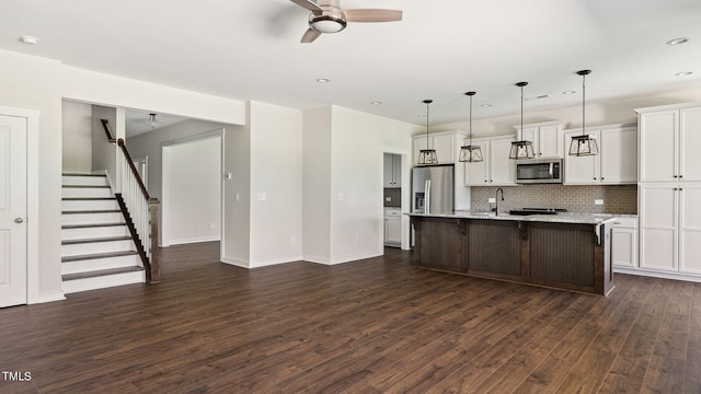 kitchen featuring a ceiling fan, stainless steel appliances, dark wood-type flooring, white cabinetry, and backsplash