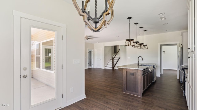 kitchen with light stone counters, dark wood-style floors, a center island with sink, visible vents, and pendant lighting