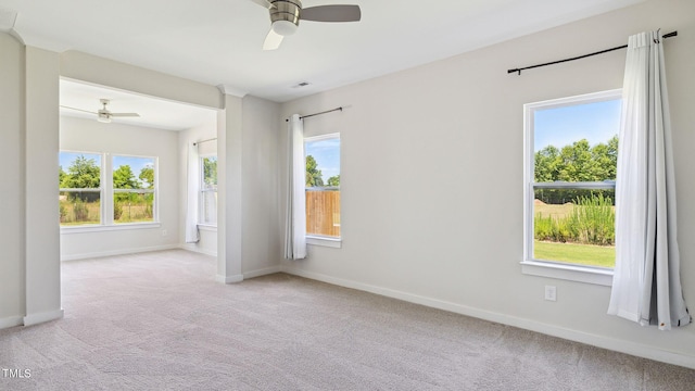 carpeted spare room with visible vents, a ceiling fan, and baseboards