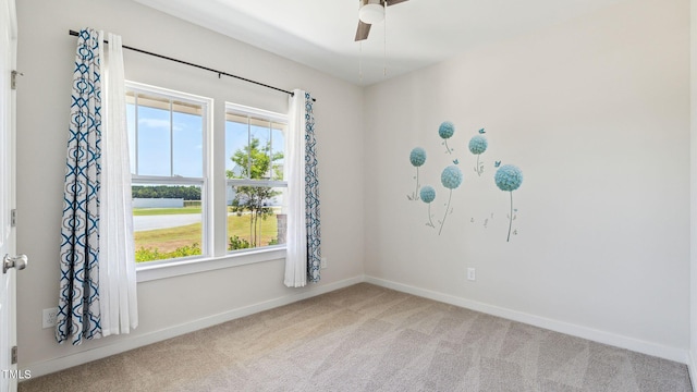 carpeted empty room with plenty of natural light, a ceiling fan, and baseboards