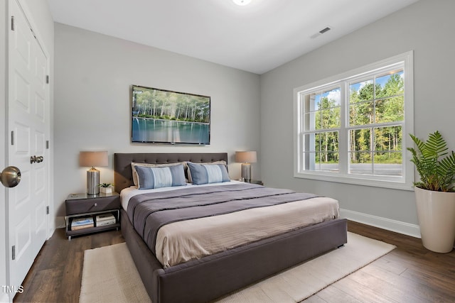 bedroom with visible vents, baseboards, and wood finished floors